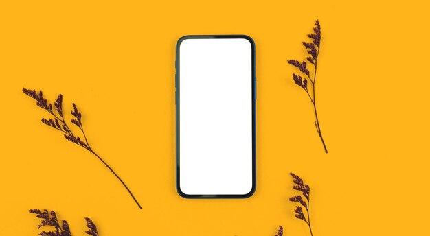 Photo home office desktop concept, flat lay of blank white screen, smartphone mockup on a yellow background with dried grass, top view photo