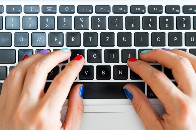 Photo home office or online shopping woman fingers with colorful nails are typing on a notebook keyboard