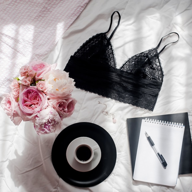 Photo home office workspace. notebook with copyspace, black lace lingerie, bouquet of roses, cof