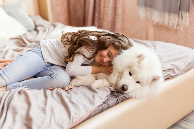 Home portrait of cute child hugging with dog on the sofa