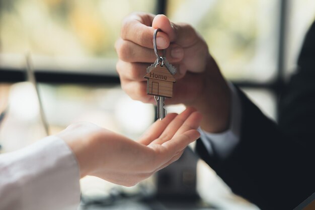 A home rental company employee is handing the house keys to a customer who has agreed to sign a rental contract explaining the details and terms of the rental Home and real estate rental ideas