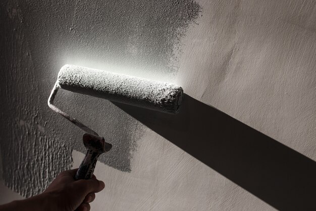 Home repairs. Painting the walls of the room in gray with a paint roller.