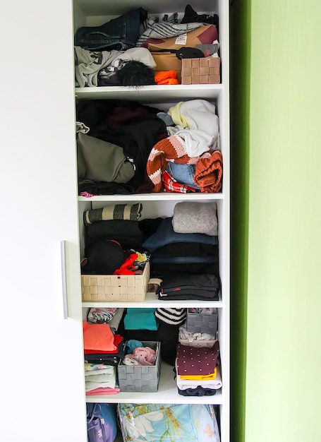 Photo home wardrobe with different clothes. small space organization. the contrast of order and disorder. vertical storage boxes