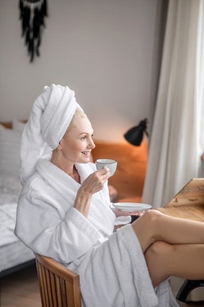 At home. A woman in a white robe relaxing at home