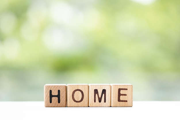 Home word is written on wooden cubes on a green summer background Closeup of wooden elements