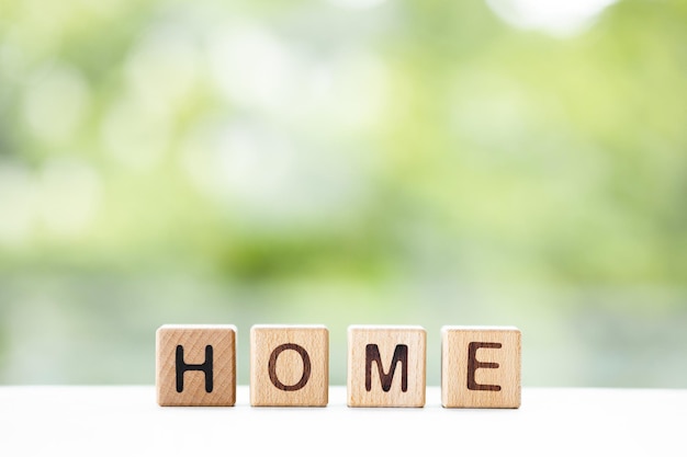 Home word is written on wooden cubes on a green summer background Closeup of wooden elements