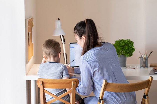 Home work concept. Working from home during the coronavirus pandemic COVID-19. Mother telecommuting while her child playing