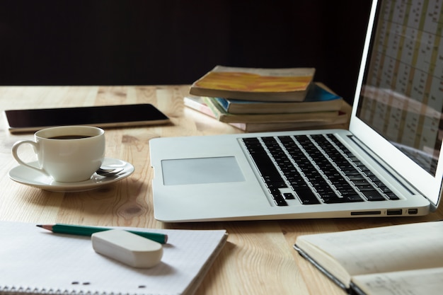 Home workplace desk with laptop, books and coffee