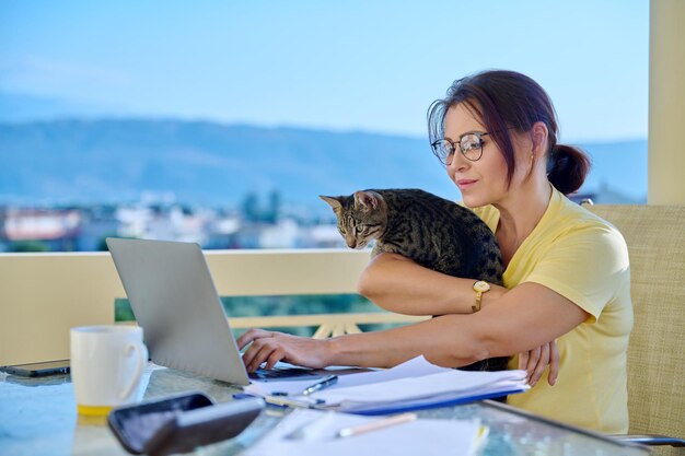 Home workplace female freelancer working remotely with pet cat in her arms