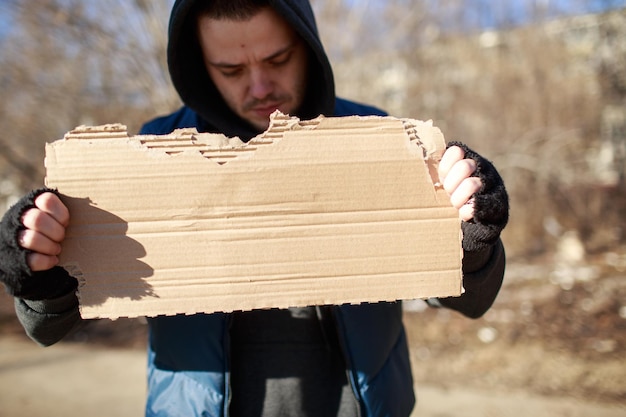 Homeless man holds blank cardboard for your text