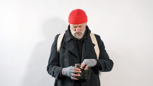 homeless man, a pensioner, an old man with a gray beard in a coat and a red hat on an isolated white background