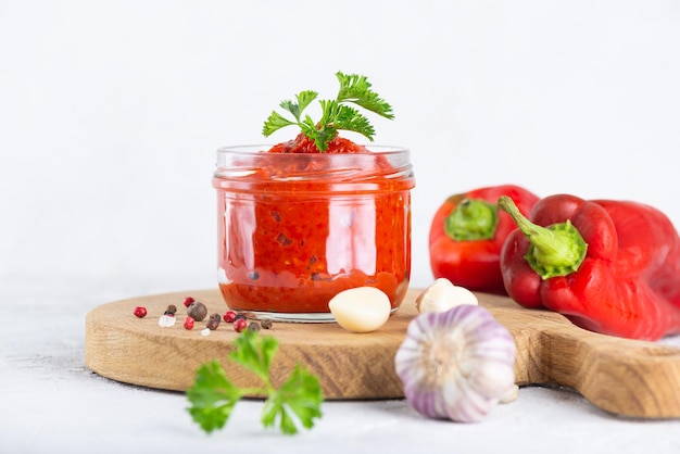 Homemade ajvar of sweet peppers tomatoes garlic and onions with spices and parsley on a wooden board