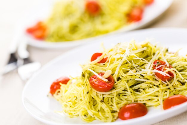 Homemade angel hair pasta with pesto sauce and roasted cherry tomatoes.