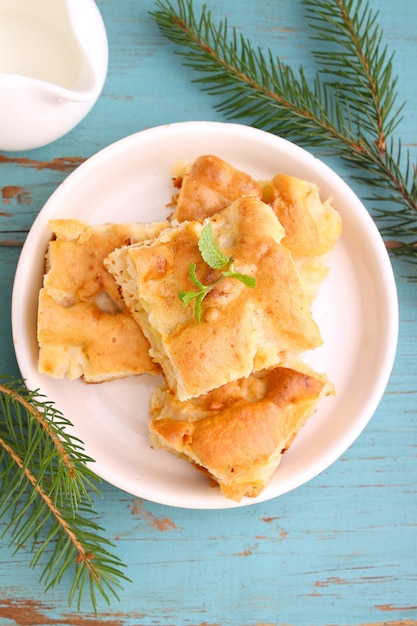 Homemade apple pie (charlotte) on a blue wooden background spruce branches