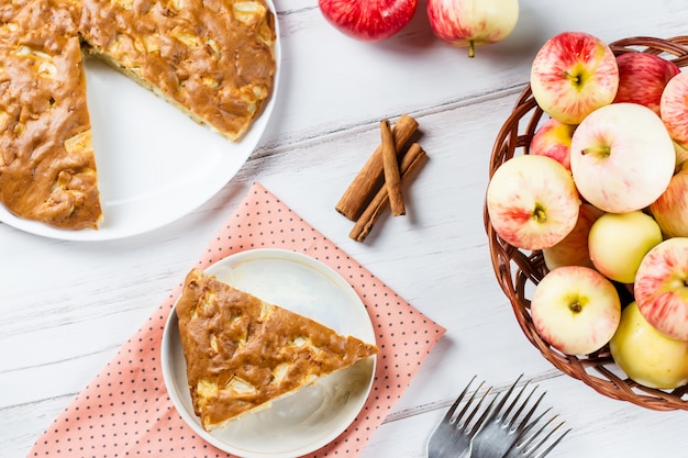 Homemade apple pie with cinnamon and fresh ripe apples in the background