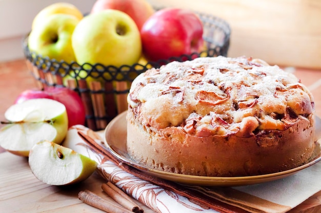 Photo homemade apple pie with cinnamon on the plate and green and red apples in the background