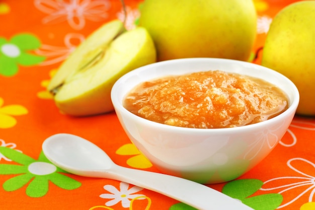 Homemade apple puree in a bowl on colorful tablecloth