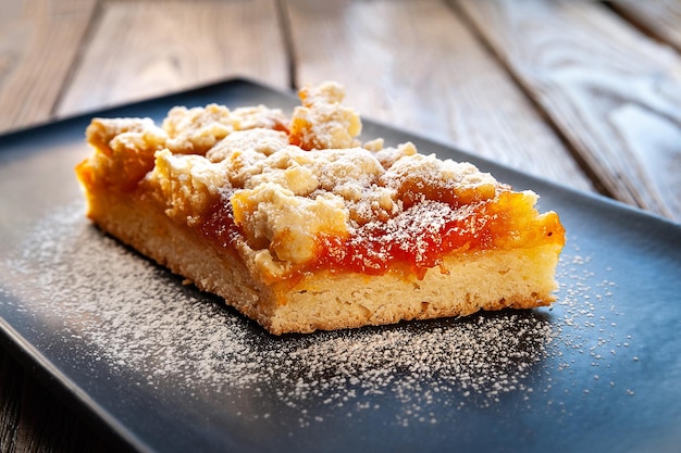 Homemade apricot pie A piece of rustic hot sweet pie in icing sugar on a black plate