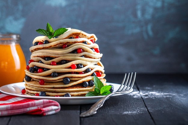 Homemade baked pancakes with fresh berries and jam jar for delicious breakfast