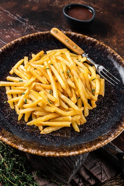 Homemade Baked Potato french fries in rustic palte with thyme. Dark background. Top view.