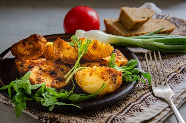 Homemade baked potatoes cooked in the country style in a clay plate and a kitchen napkin Home c