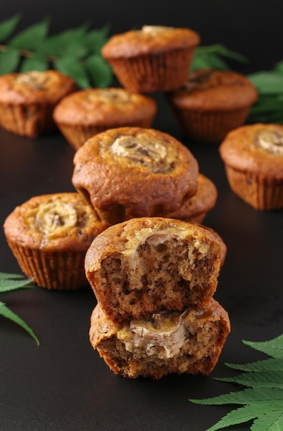 Homemade banana muffins with a slice of banana and cinnamon on dark background