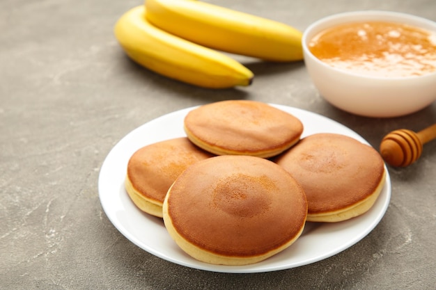 Homemade banana pancakes with butter in plate on grey background Space for text