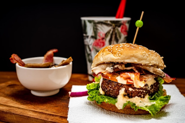 Homemade beef burger with lettuce tomato mushrooms and cheese on a wooden board with black background Chopped view Copy text Fastfood concept