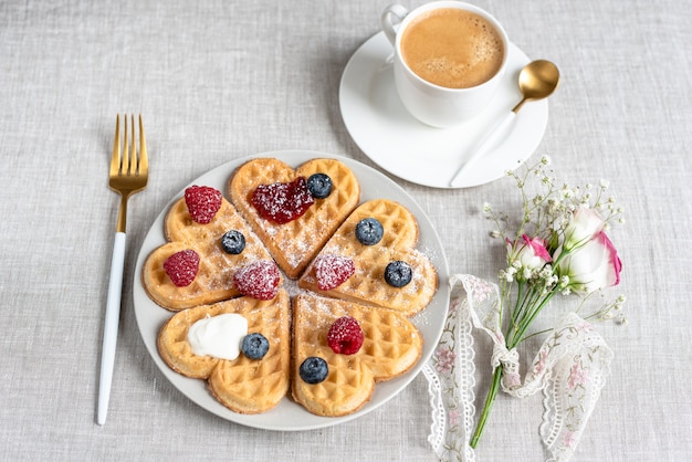 Homemade Belgian heart waffles with strawberry sauce and berries with flowers