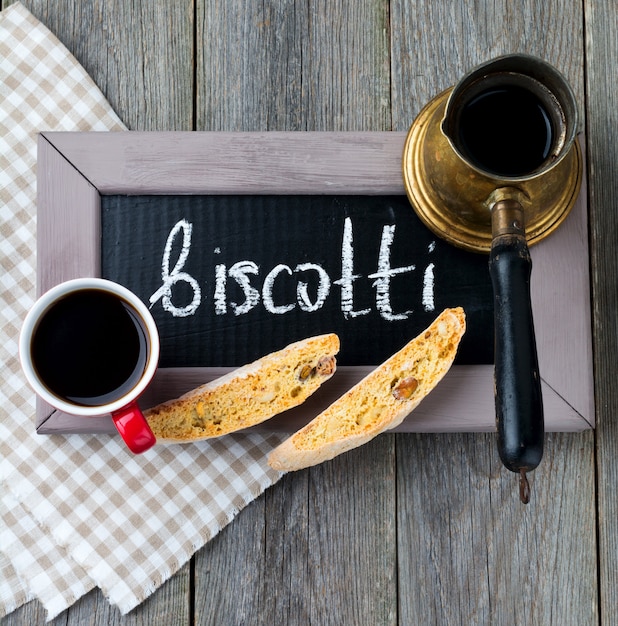 Photo homemade biscotti with nuts and a cup of coffee on the old wooden table background.