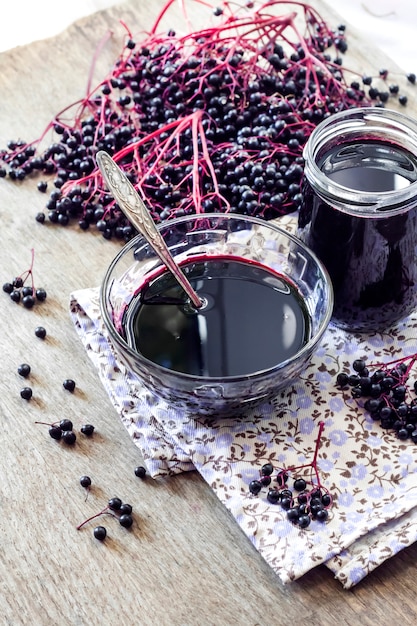 Homemade black elderberry syrup in glass bowl and jar