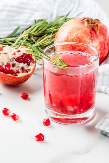 Homemade boozy alcoholic pomegranate cocktail with rosemary and vodka, white marble , 