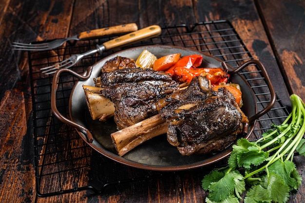 Homemade Braised Lamb Shanks with Sauce and Herbs in a steel tray Wooden background Top view