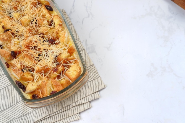 Homemade bread butter pudding with raisins and grated cheese as topping