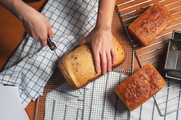 Homemade bread on kitchen table with woman hand cutting