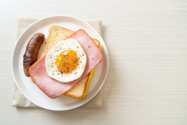 homemade bread toasted cheese topped ham and fried egg with pork sausage for breakfast