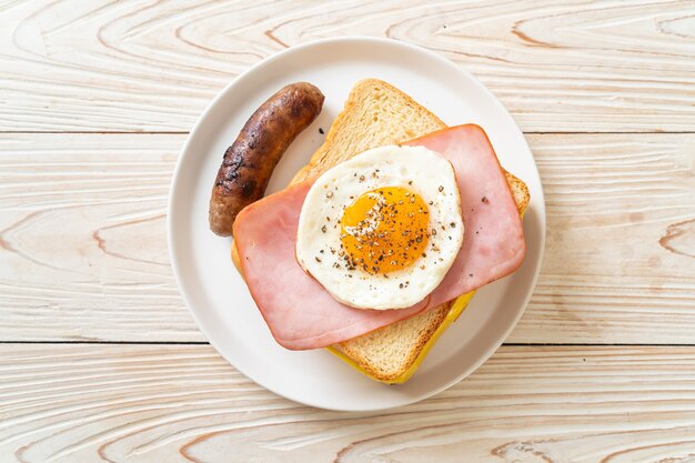 homemade bread toasted cheese topped ham and fried egg with pork sausage for breakfast