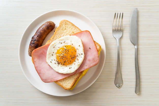 homemade bread toasted cheese topped ham and fried egg with pork sausage for breakfast