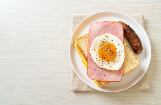 homemade bread toasted cheese topped ham and fried egg with pork sausage for breakfast