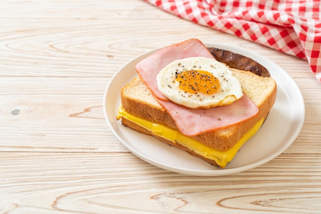 homemade bread toasted cheese topped ham and fried egg with pork sausage for breakfast