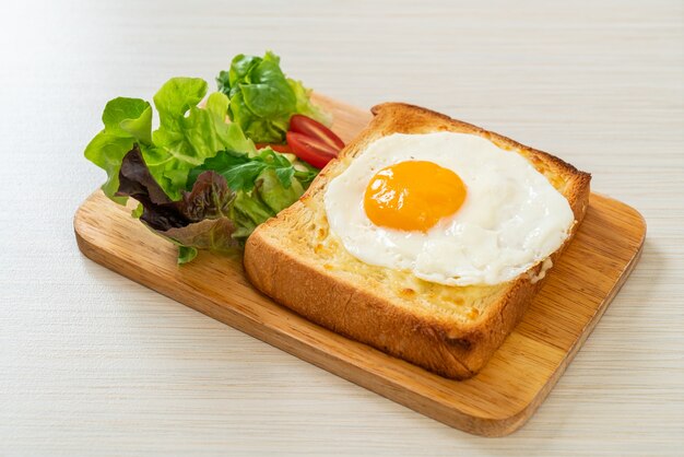 homemade bread toasted with cheese and fried egg on top with vegetable salad for breakfast