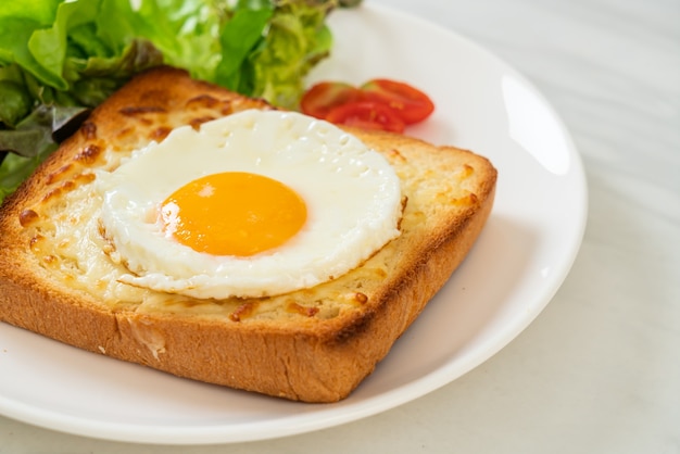 homemade bread toasted with cheese and fried egg on top with vegetable salad for breakfast