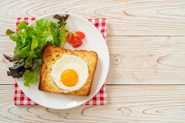 homemade bread toasted with cheese and fried egg on top with vegetable salad for breakfast