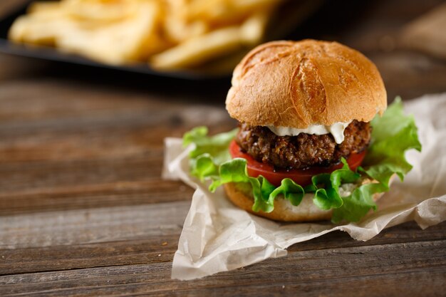 Homemade burger with french fries on wooden table