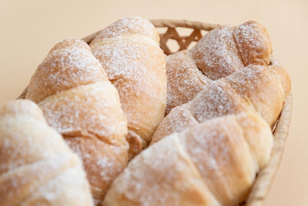 Homemade butter croissants sprinkled with powdered sugar on wicker tray