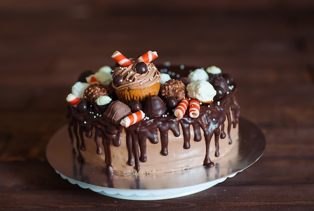 Homemade cake decorated with sweets, cupcakes and waffles.