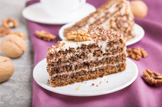 Homemade cake with milk cream and walnuts with cup of coffee on gray concrete 