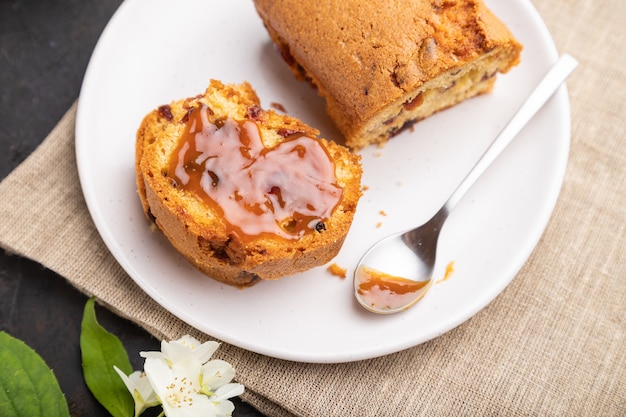 Homemade cake with raisins, almonds, soft caramel and a cup of coffee on a black concrete surface and linen textile