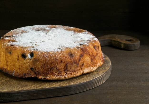 Homemade cake on wooden Board, on black background.