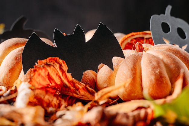 Homemade cakes in shape of halloween pumpkin with autumn leaves on dark